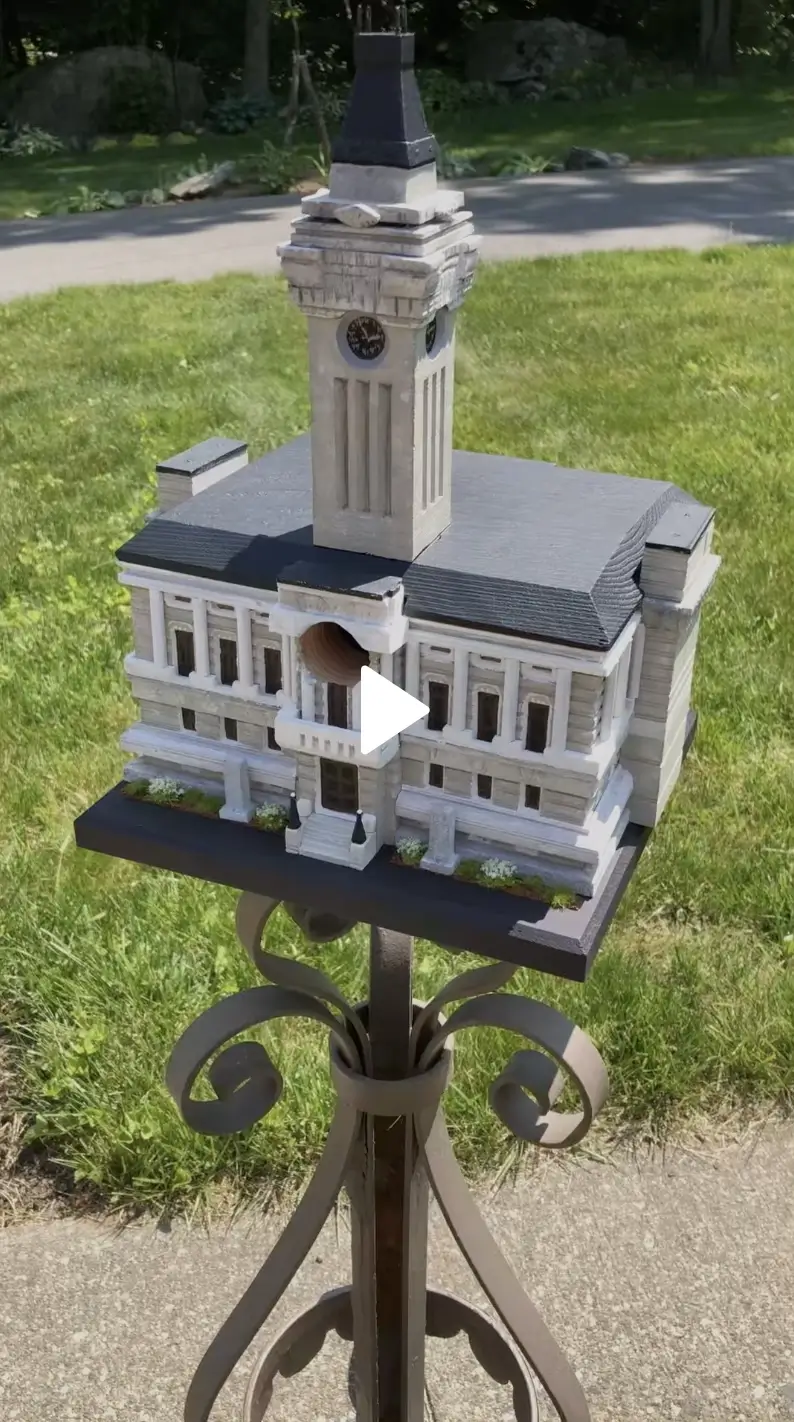 Replica of a municipal building with a clock tower, on a wrought-iron stand